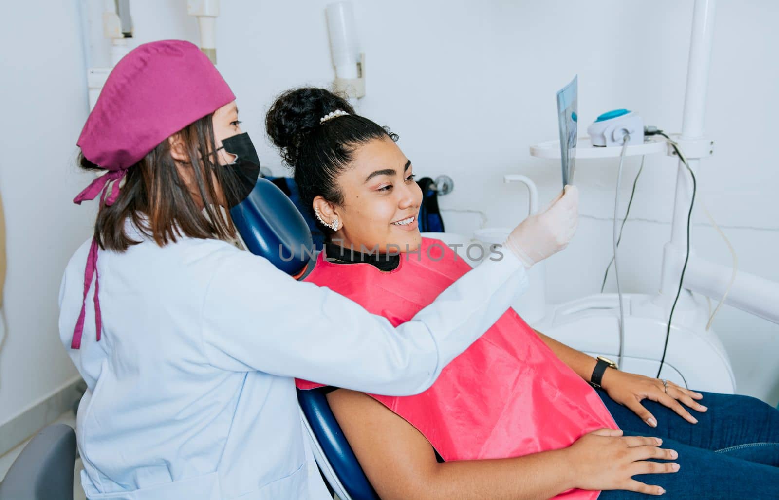 Dentist showing patient x-ray, Dentist with patient reviewing the x-ray. Patient looking at x-ray with dentist, Concept of dentist showing x-ray examination to female patient by isaiphoto