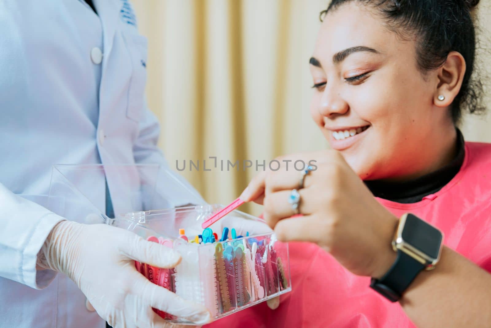 Dental patient choosing dental braces, Patient with dentist choosing colored rubber band. Patient with dentist choosing dental braces by isaiphoto