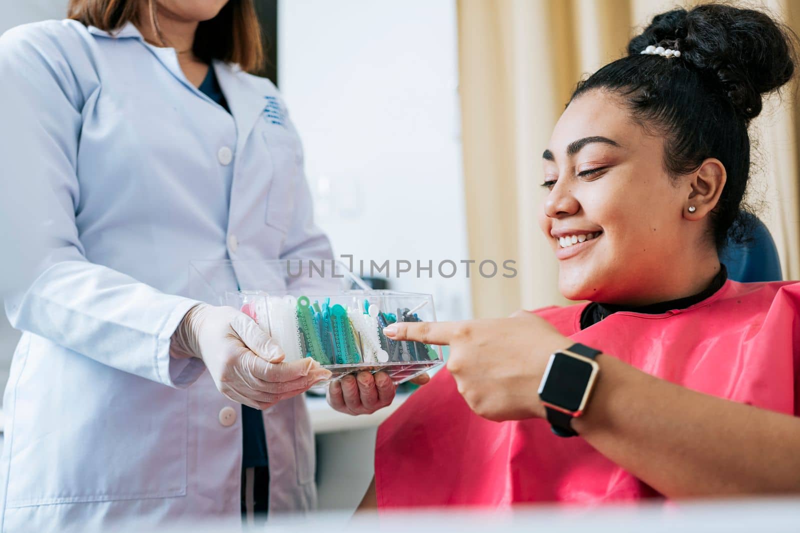 Dental patient choosing dental braces, Patient with dentist choosing colored rubber band. Patient with dentist choosing dental braces by isaiphoto