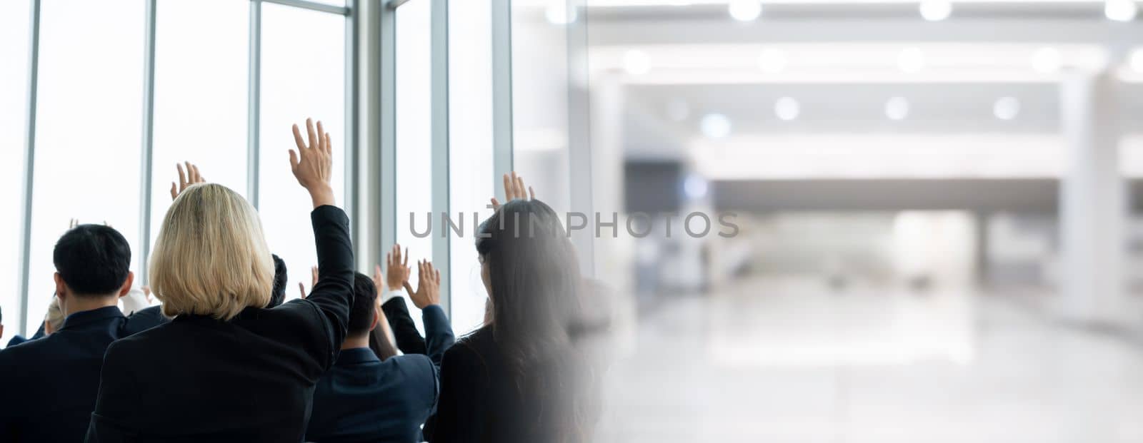 Group of business people meeting in a seminar conference widen view . Audience listening to instructor in employee education training session . Office worker community summit forum with speaker .