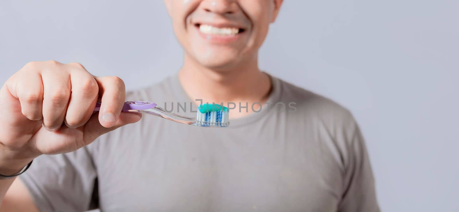 Young man showing toothbrush with toothpaste isolated, guy holding brush with toothpaste on white background, Person showing a toothbrush with toothpaste by isaiphoto
