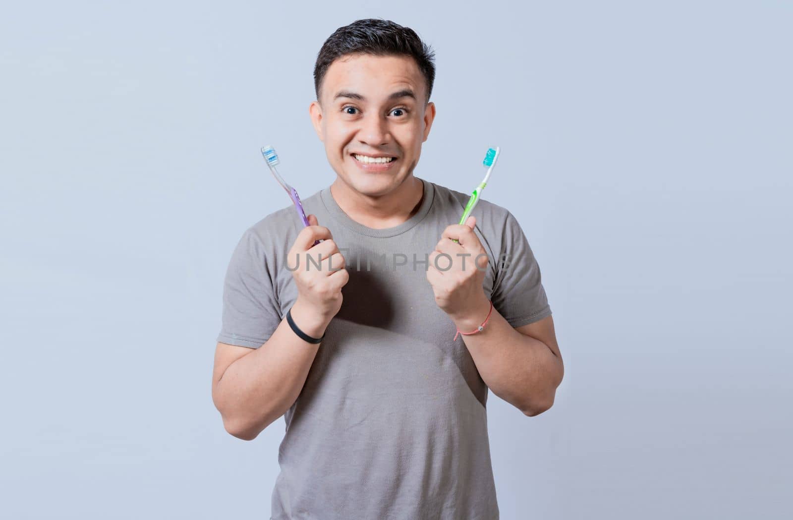Smiling guy holding two toothbrushes isolated. Smiling people showing two toothbrushes isolated, Handsome man holding two toothbrushes isolated
