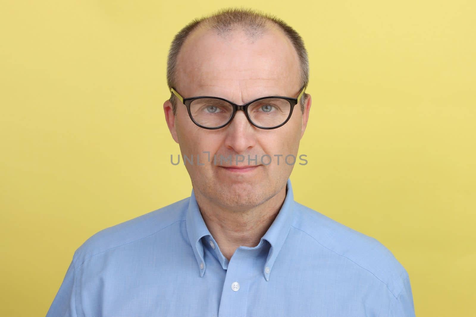 Portrait of a handsome older man wearing a blue shirt and glasses. by gelog67