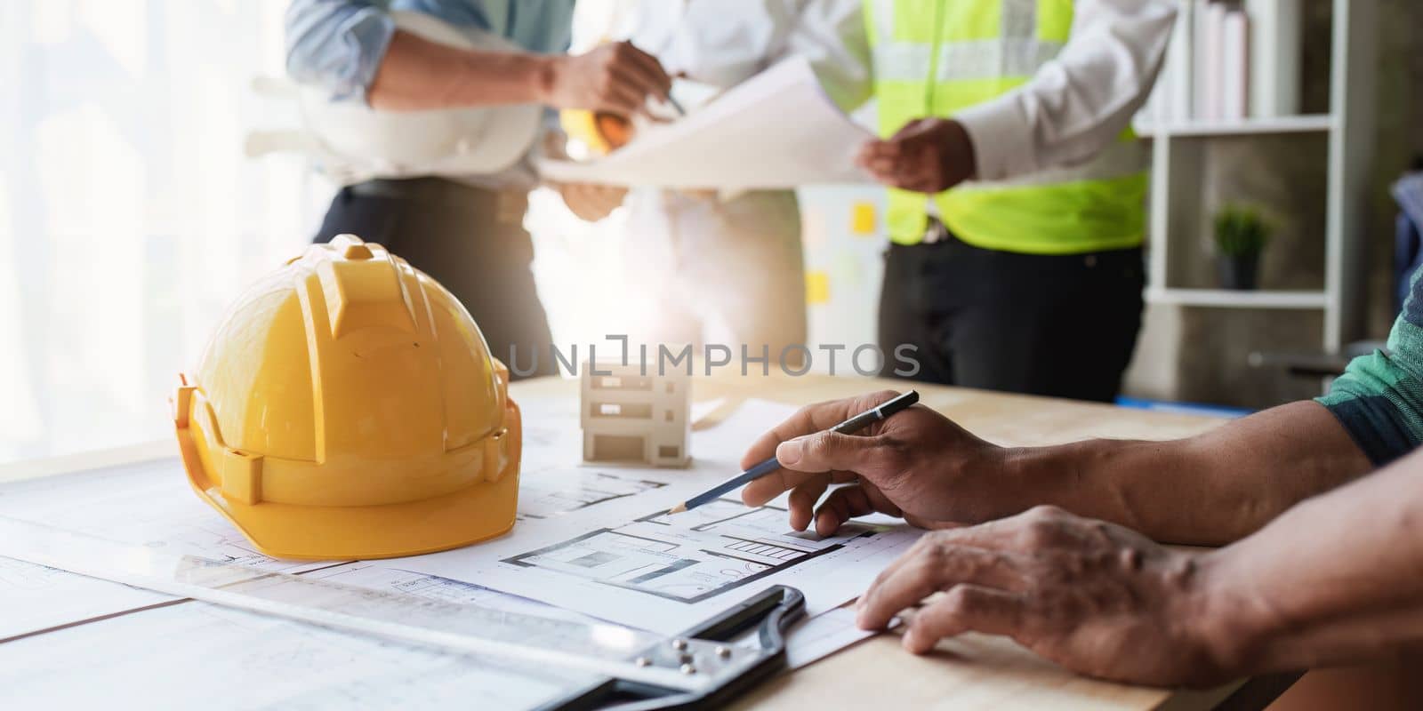 Architect team working with blueprints for architectural plan, engineer sketching a construction project, green energy concept.