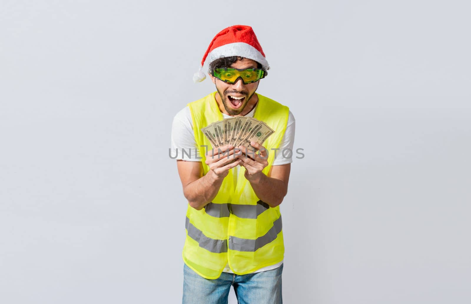 Builder engineer in christmas hat with happy expression holding dollars isolated. Concept of engineer with money in holiday season, Engineer in christmas hat holding money smiling at camera