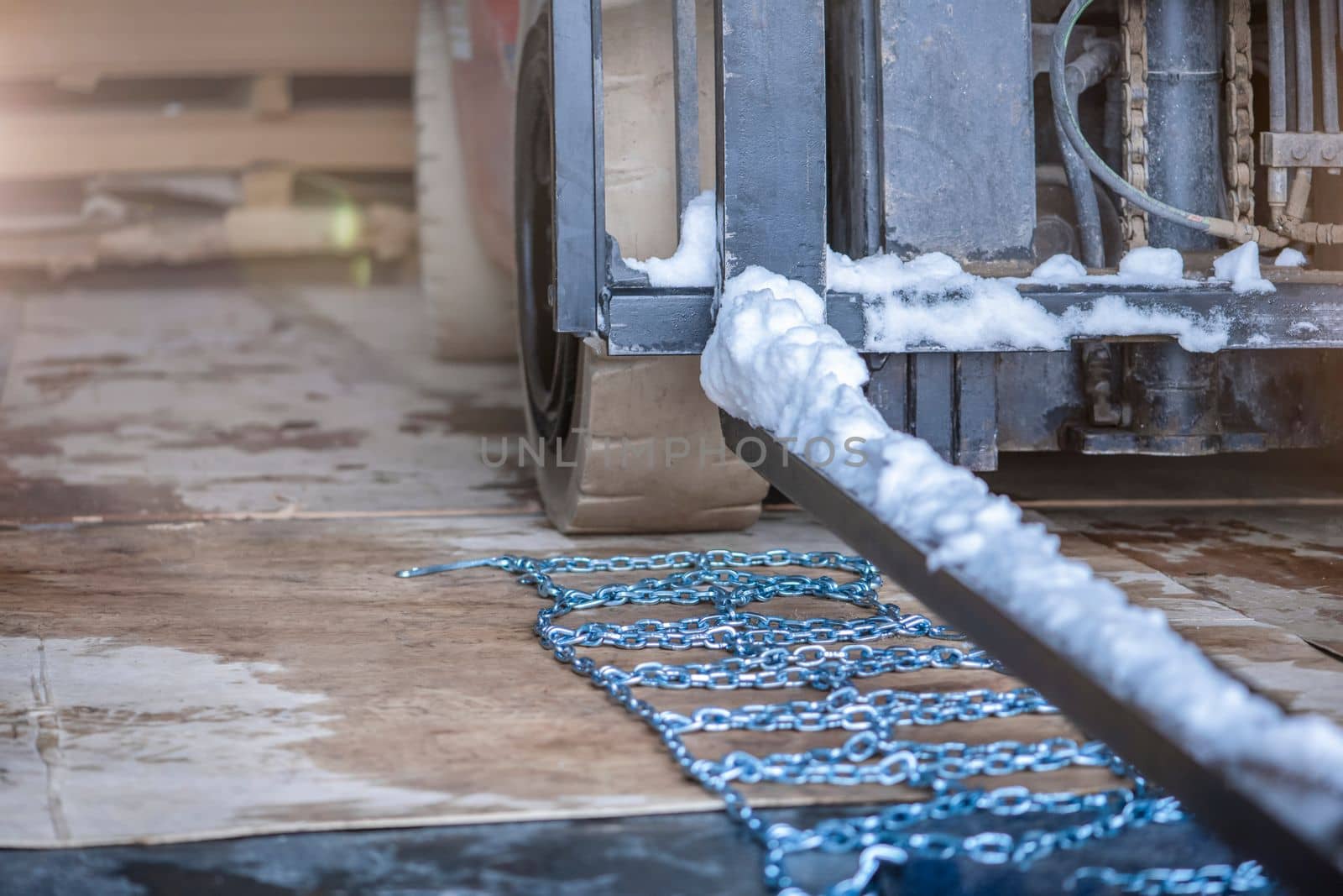 The process of installing an anti-skid chain on a wheel in winter. Preparing a loader, tractor or truck for a snowy road. Snow chains close up by SERSOL