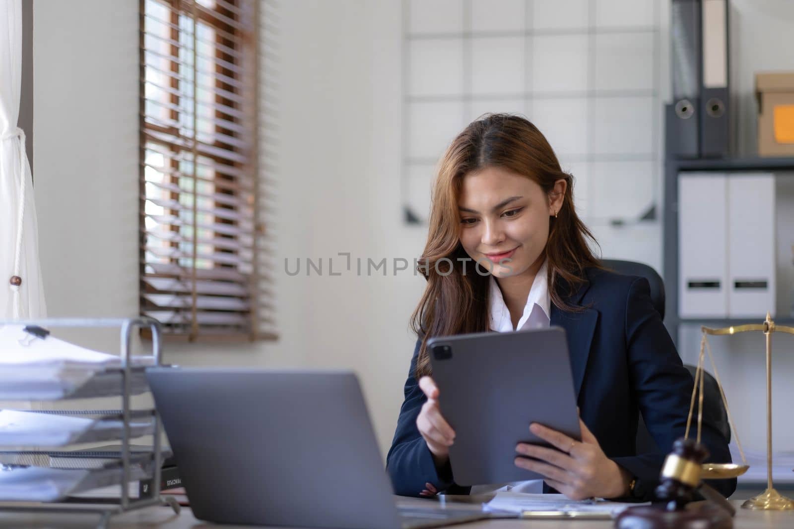 Attractive young lawyer in office Business woman and lawyers discussing contract papers with brass scale on wooden desk in office. Law, legal services, advice, Justice and real estate concept...