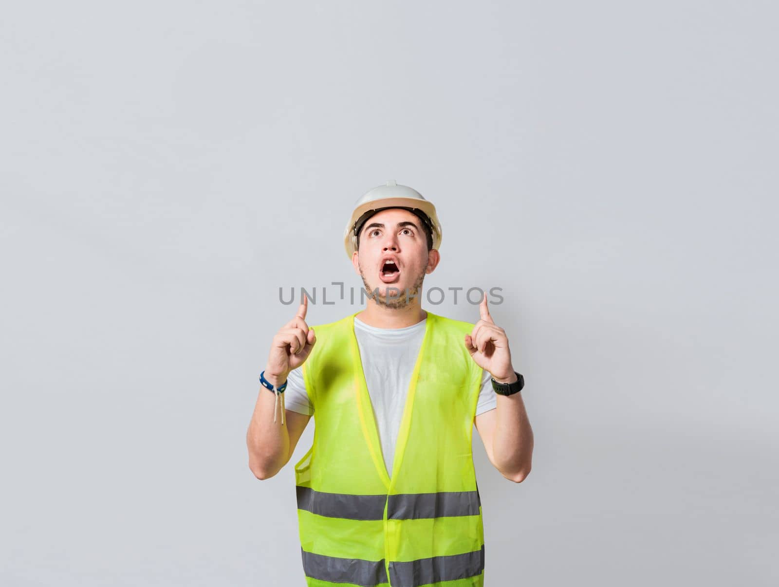 Amazed engineer pointing at an advertisement. Concept of an engineer with astonished face pointing at blank space, Amazed engineer man pointing up, Surprised young architect pointing up
