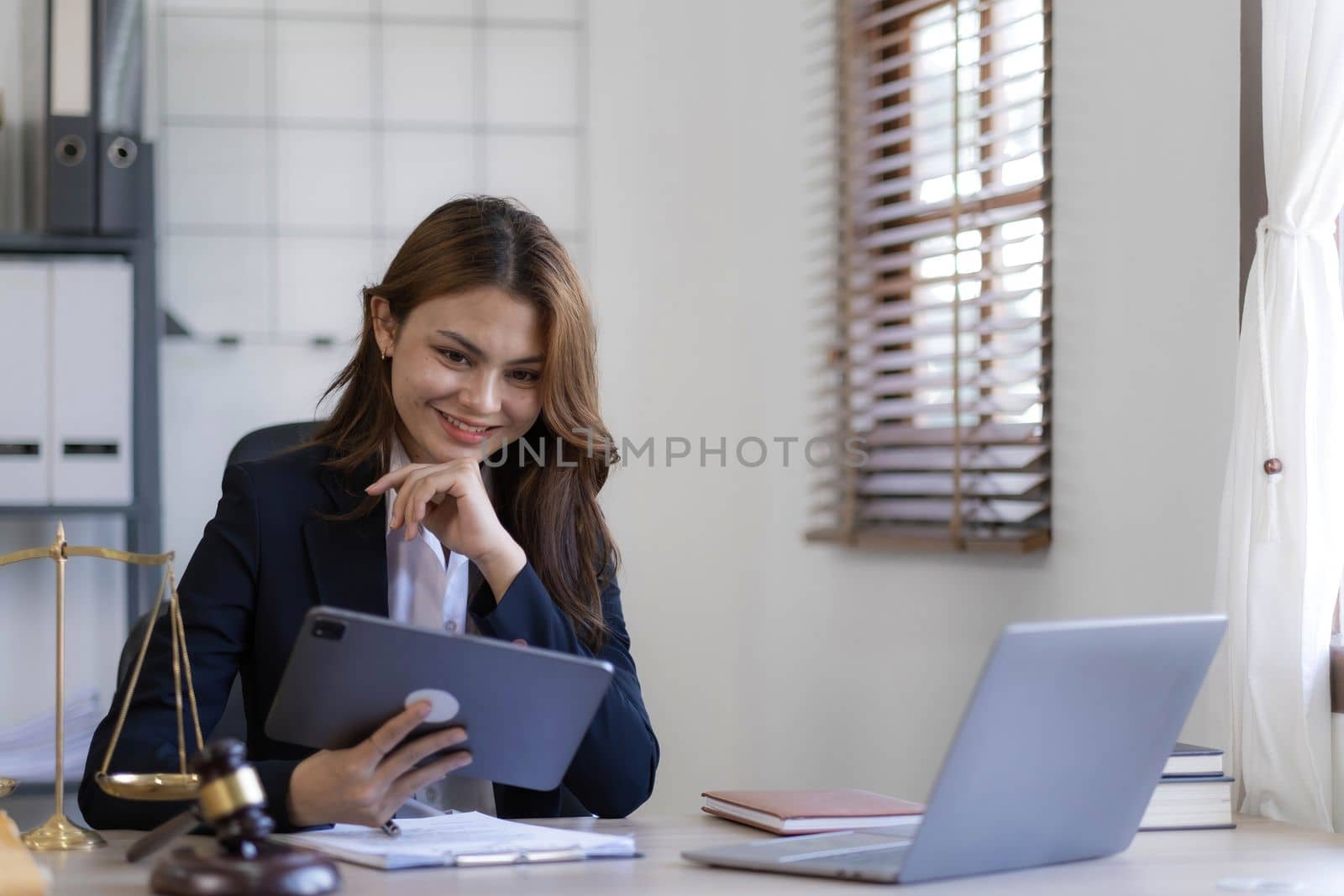 Attractive young lawyer in office Business woman and lawyers discussing contract papers with brass scale on wooden desk in office. Law, legal services, advice, Justice and real estate concept...