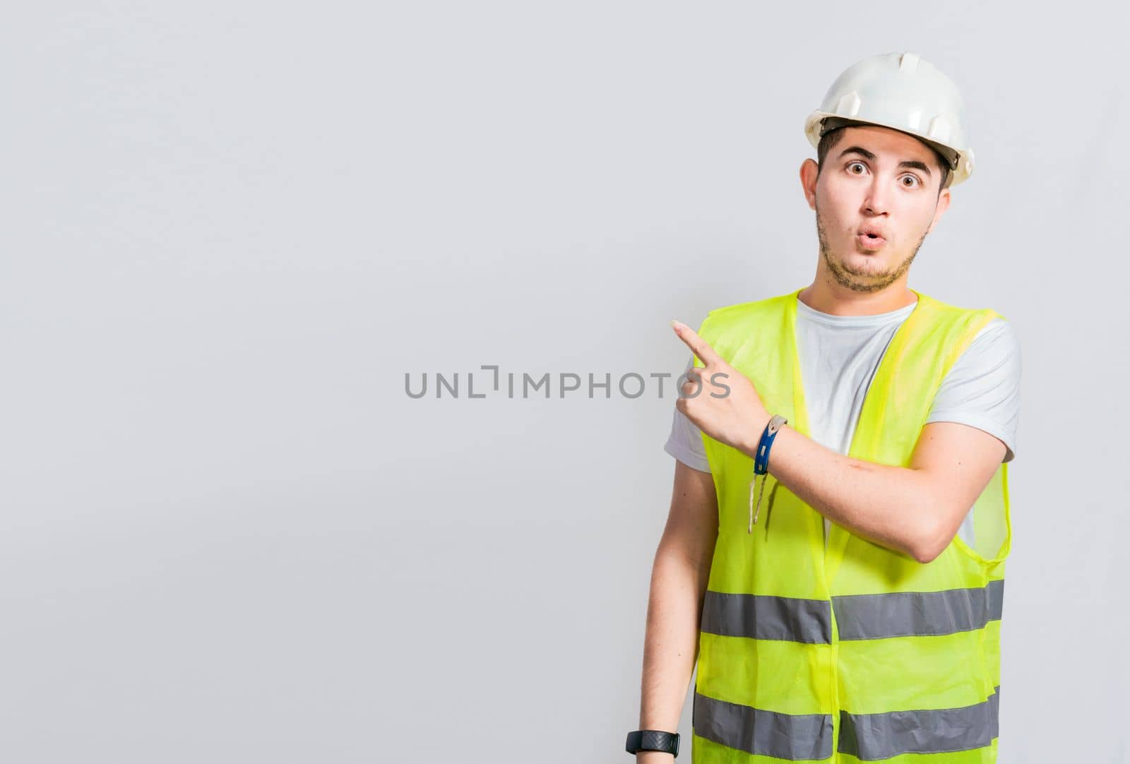 Surprised face construction worker pointing at an advertisement. Engineer man pointing to side. Surprised face engineer pointing finger to the right, Surprised engineer pointing to the side