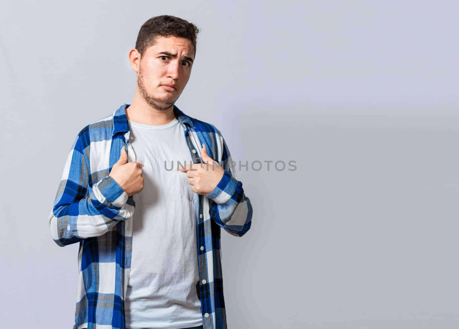 Confused caucasian young man pointing at himself. Confused person pointing at himself isolated. Confused latin guy pointing at himself isolated, Portrait of confused teenager pointing at himself