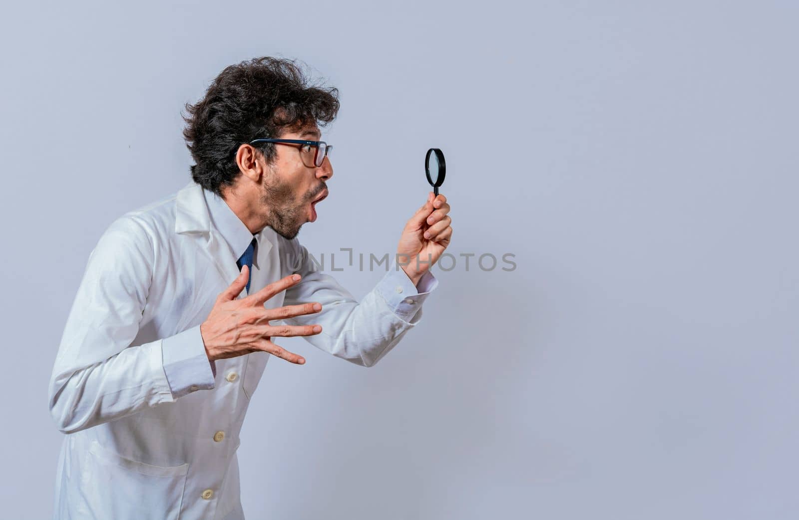 Scientist holding a magnifying glass looking to the side, Man in a white coat with a magnifying glass looking advertisement, Surprised scientist observing with a magnifying glass to the side