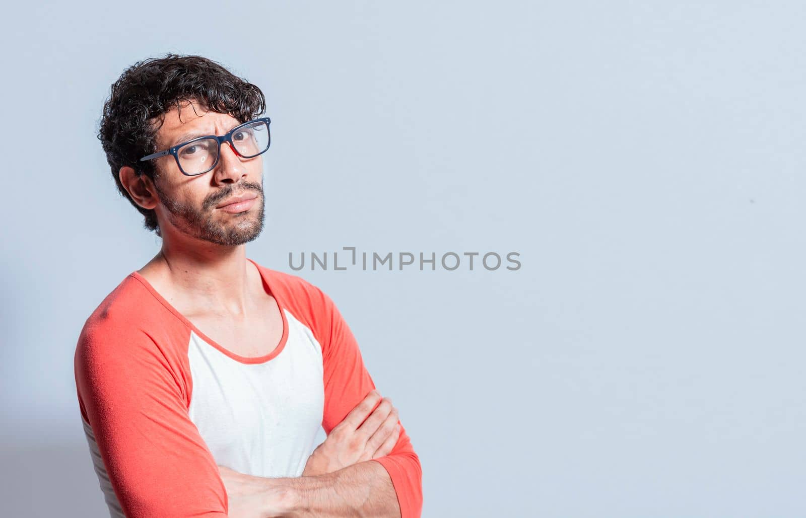 Young latin man in glasses with crossed arms looking in profile at the camera. Nicaraguan man with crossed arms looking at the camera isolated, Portrait of young man with crossed arms isolated