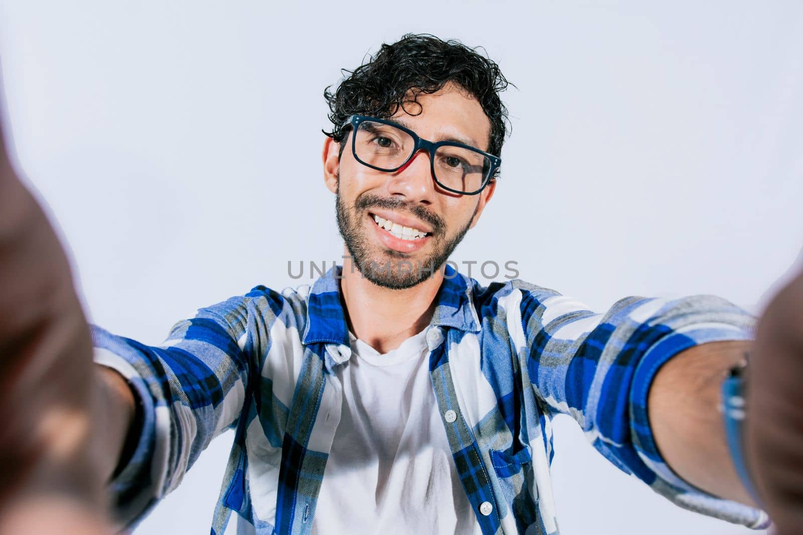 Handsome man taking a selfie looking at the camera on isolated background. Teenage guy taking a self portrait isolated. Guy with beard and glasses taking a self portrait isolated