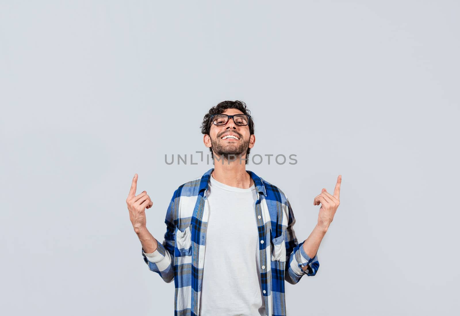 Smiling man in glasses pointing fingers up, People recommending something with fingers up isolated, Young man pointing an advertisement with fingers up