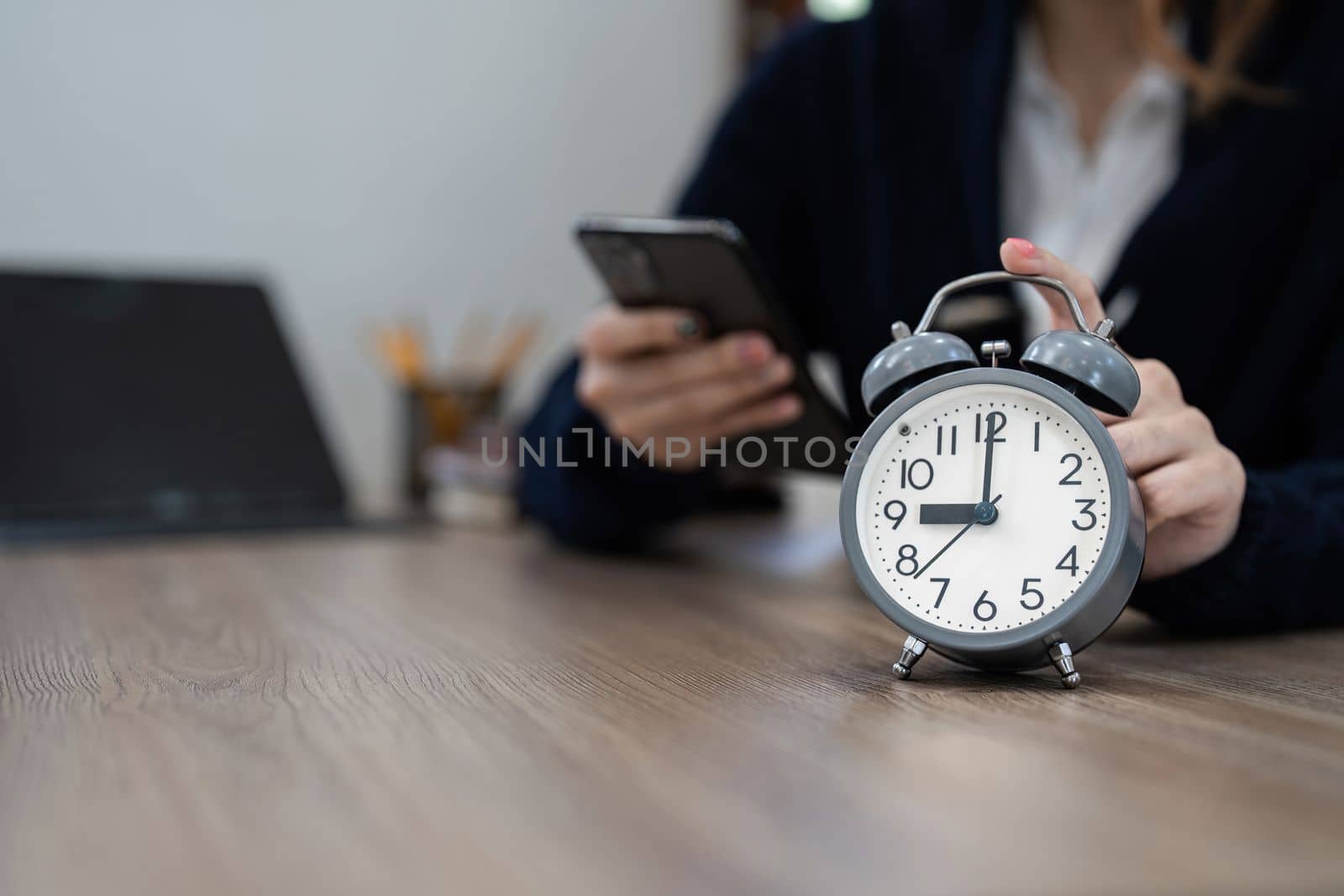 Alarm clock on wooden table with business working at home. Time concept at early morning or overtime in evening.