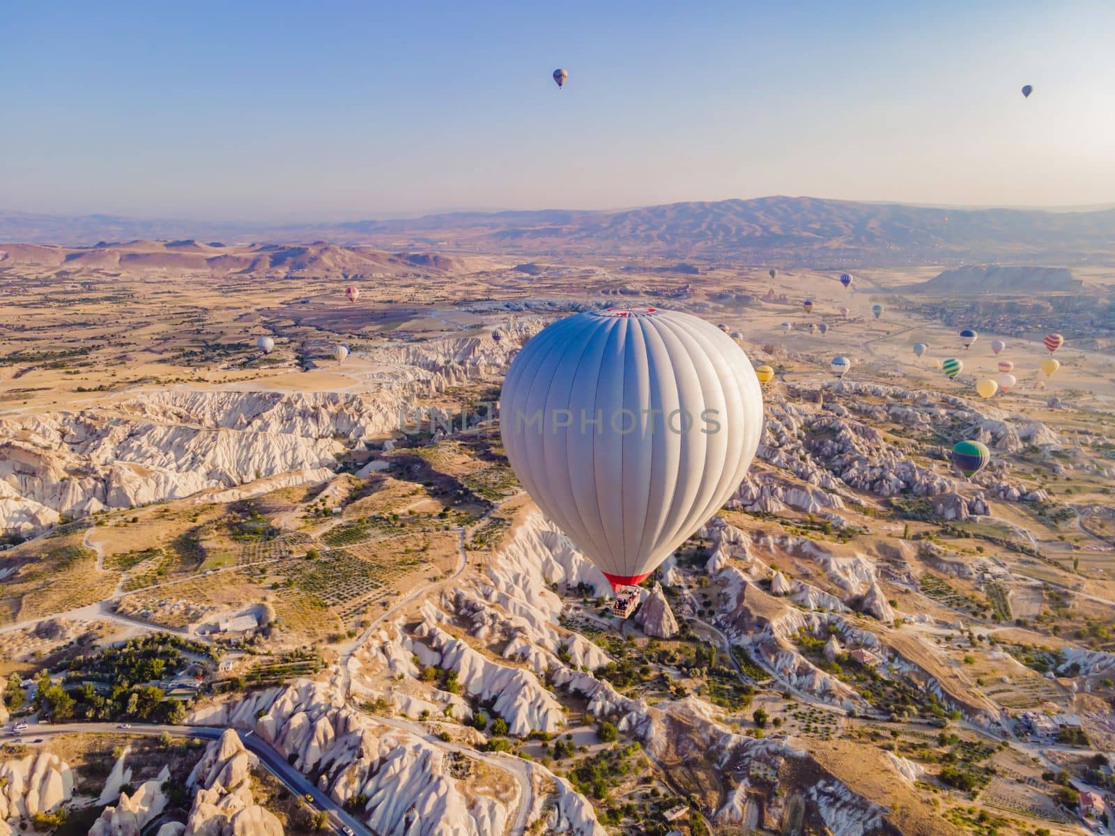 Colorful hot air balloons flying over at fairy chimneys valley in Nevsehir, Goreme, Cappadocia Turkey. Spectacular panoramic drone view of the underground city and ballooning tourism. High quality by galitskaya