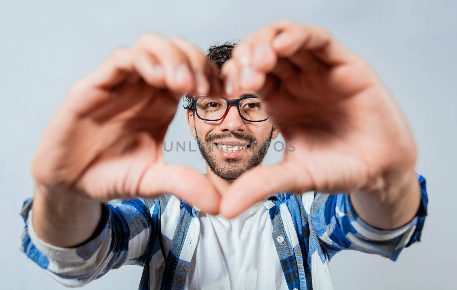 Person putting hands together in a heart shape. Teenage guy making heart shape with hands isolated. Happy man making heart shape with hands isolated