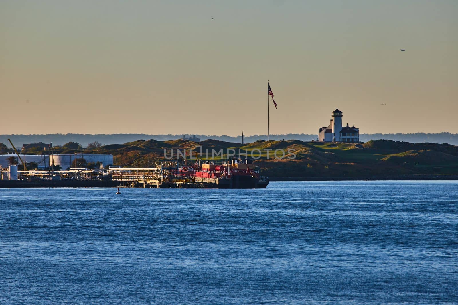 Image of Bayonne Golf Club with American Flag and industrial ships from ferry with soft golden light