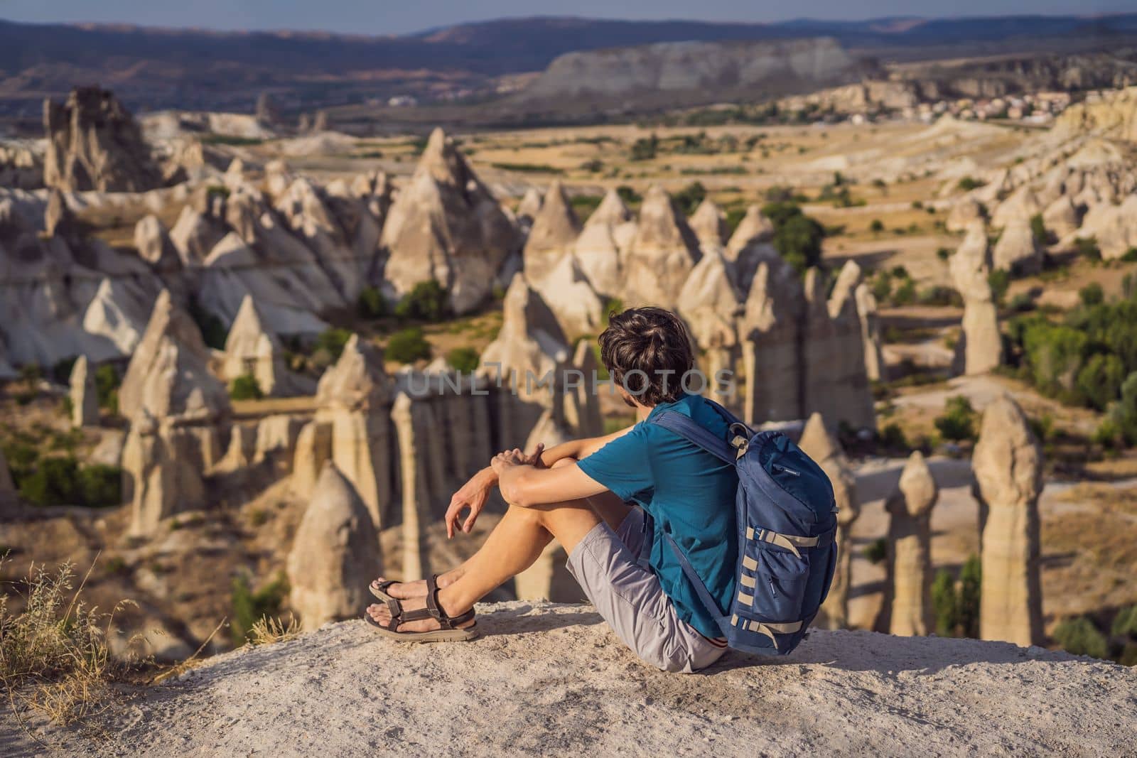 Young man exploring valley with rock formations and fairy caves near Goreme in Cappadocia Turkey.