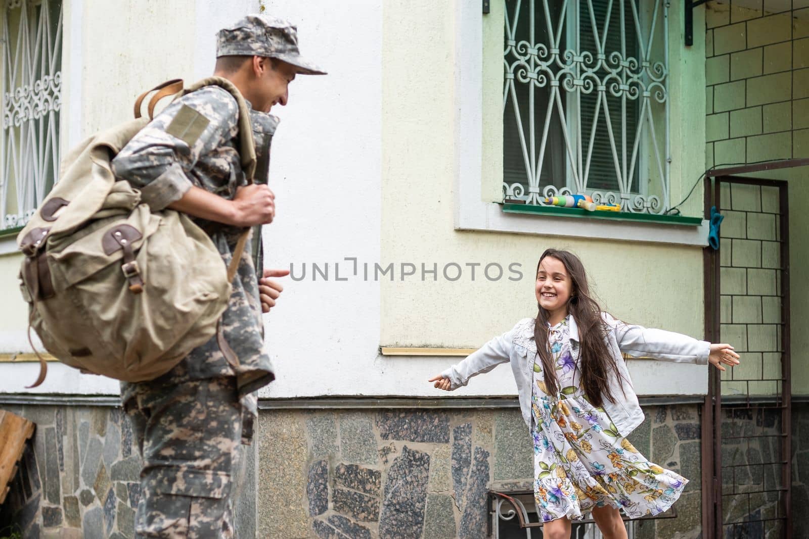 Little child is very happy her father came back from army. Little kid is hugging her father.