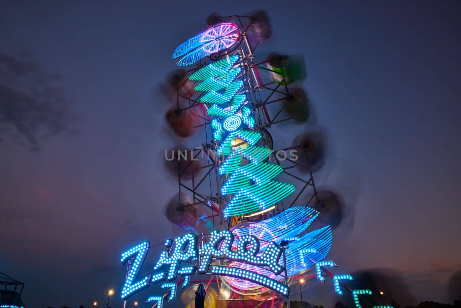 Zipper carnival ride with blurred lights during dusk at county fair by njproductions