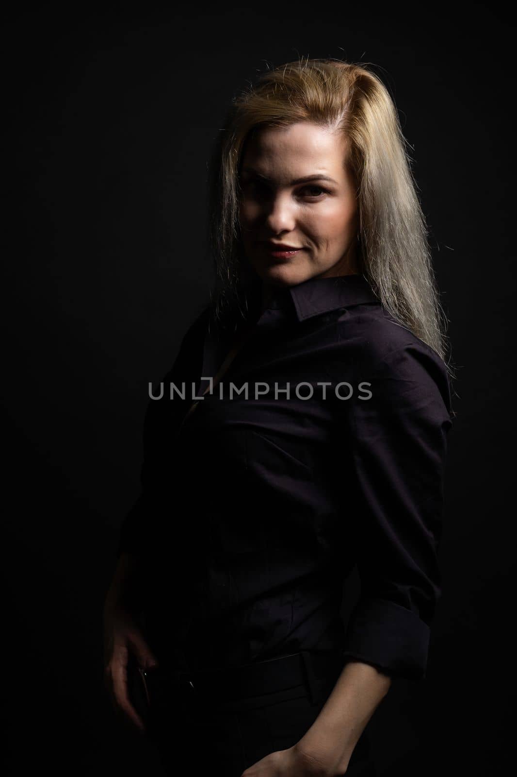 Beautiful middle-aged woman on a gray background in a black blouse