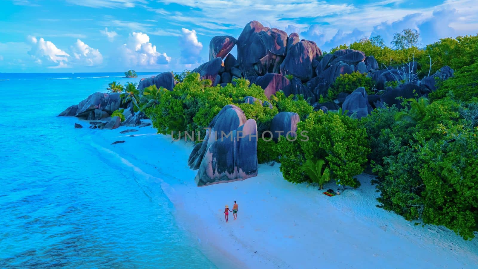 Anse Source d'Argent beach, La Digue Island, Seychelles, view. of tropical Island, couple men, and woman walking at the beach during sunset at a luxury vacation in Seychelles
