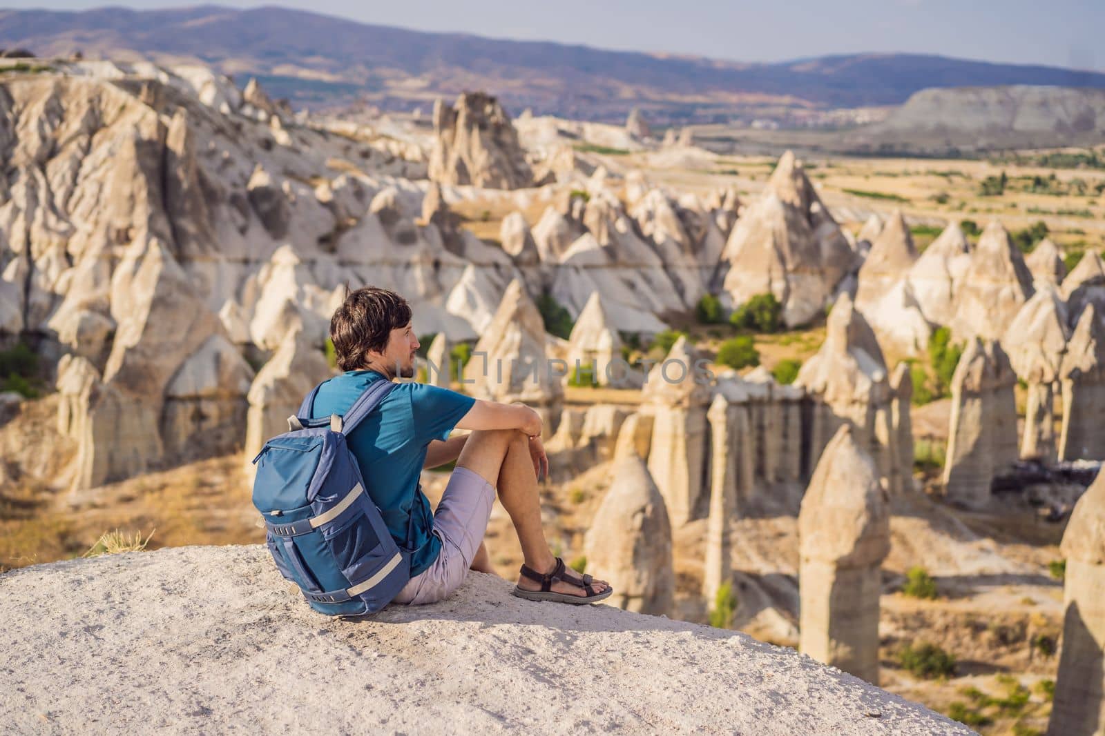 Young man exploring valley with rock formations and fairy caves near Goreme in Cappadocia Turkey.