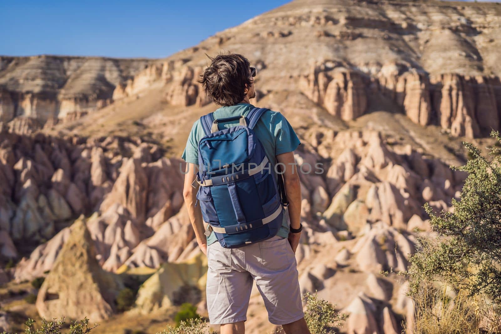 Young man exploring valley with rock formations and fairy caves near Goreme in Cappadocia Turkey.