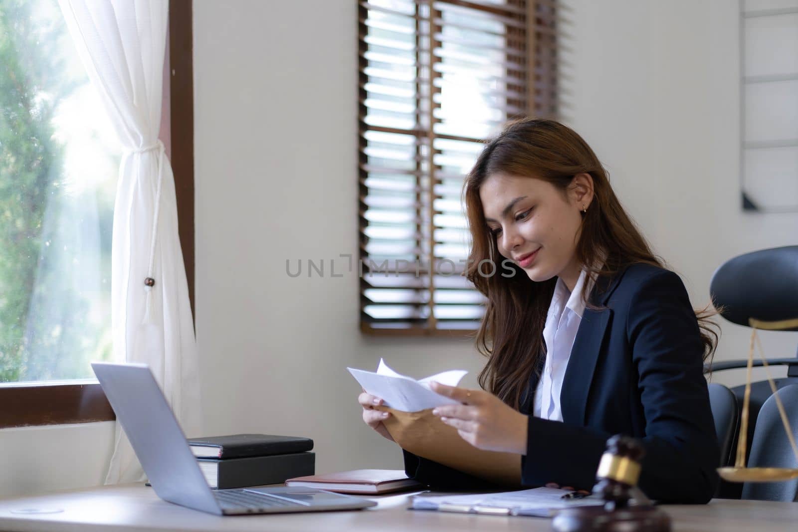 Attractive young lawyer in office Business woman and lawyers discussing contract papers with brass scale on wooden desk in office. Law, legal services, advice, Justice and real estate concept. by wichayada