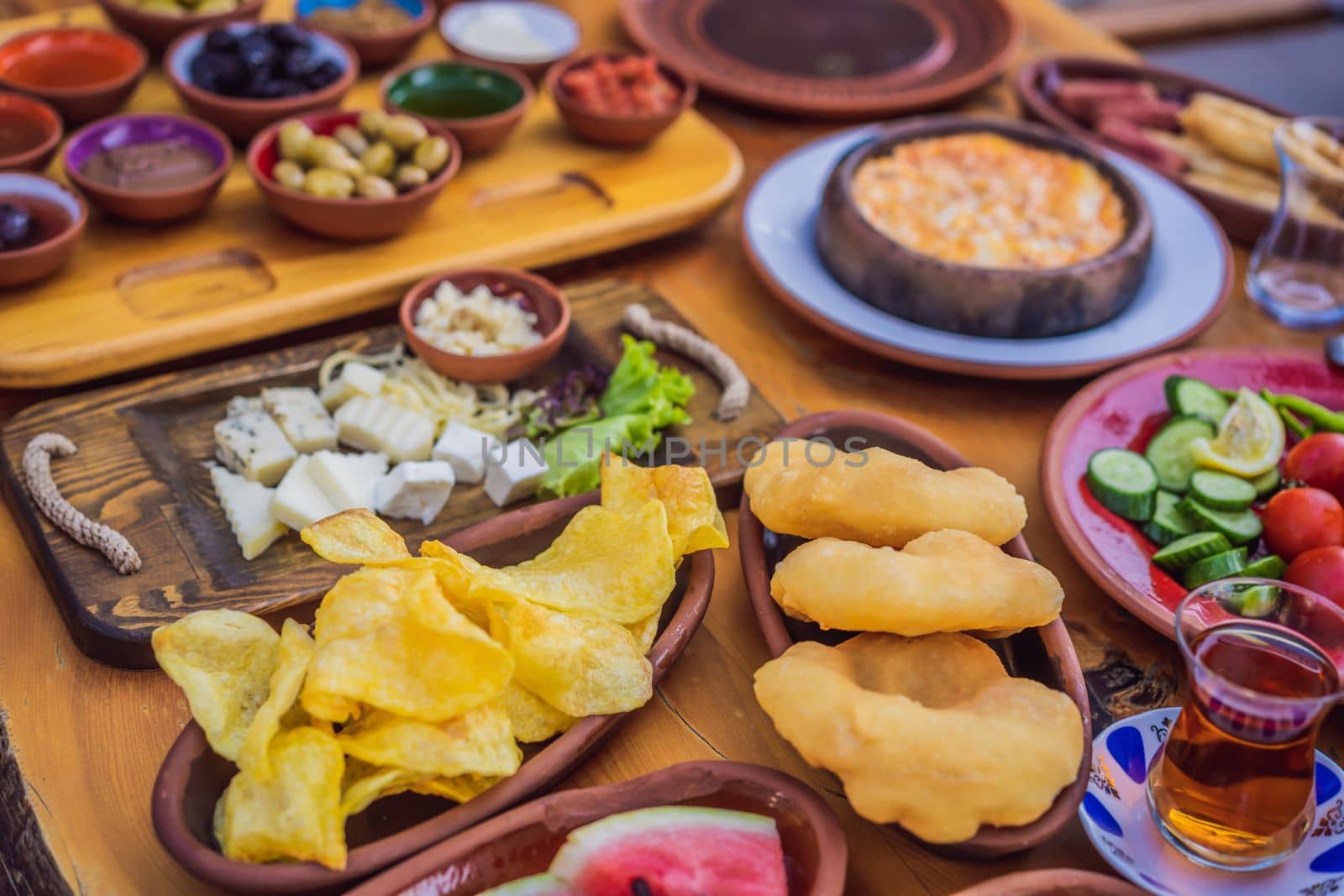 Turkish breakfast table. Pastries. Vegetables. Olives. Cheeses, fried eggs. Jams, tea in copper pot and tulip glasses. Wide composition.