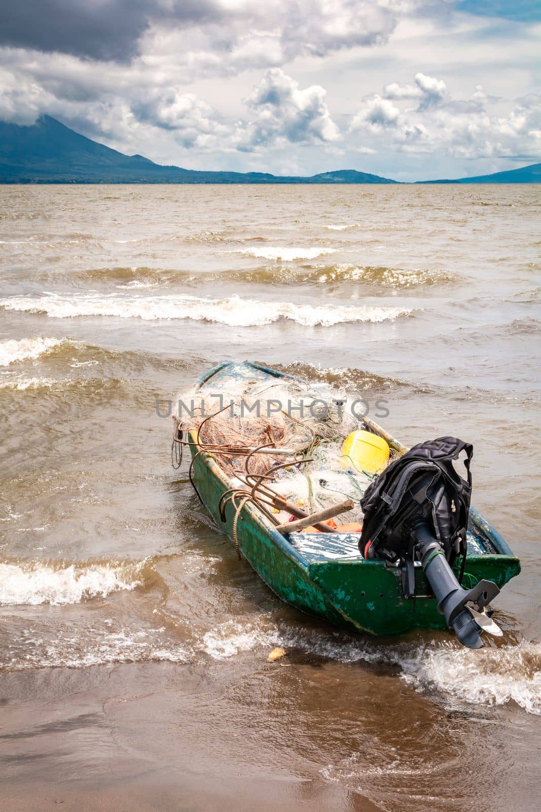 A fishing boat on the shore of a lake with volcanoes in the background. A fishing boat on a lake in Nicaragua. Concept of fishing boats parked at the seaside, Fishing boat on the shore of a lake by isaiphoto