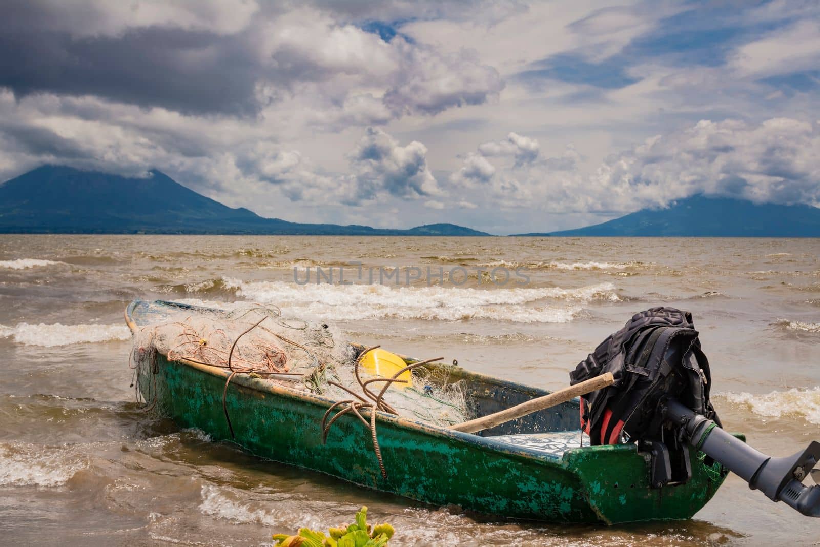 A fishing boat on a lake in Nicaragua. Concept of fishing boats parked at the seaside, Fishing boat on the shore of a lake, A fishing boat on the shore of a lake with volcanoes in the background