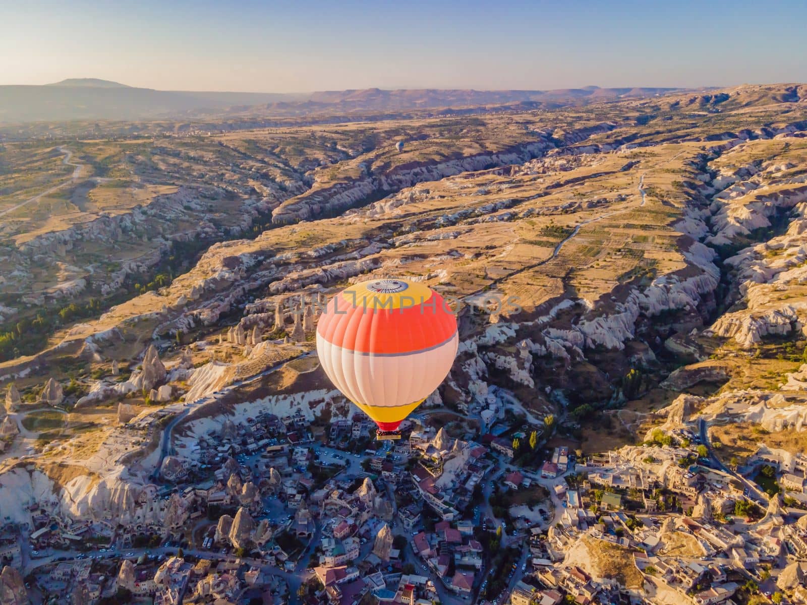 Colorful hot air balloons flying over at fairy chimneys valley in Nevsehir, Goreme, Cappadocia Turkey. Spectacular panoramic drone view of the underground city and ballooning tourism. High quality.