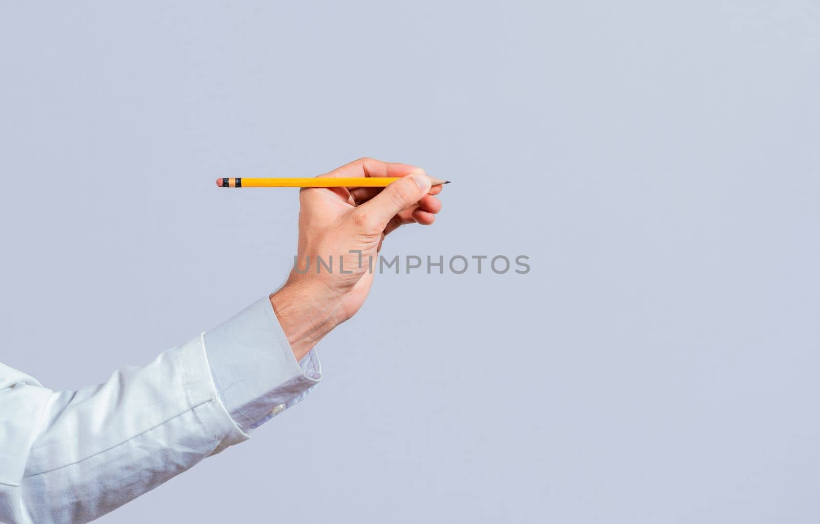 Male hand holding a pencil on a blank. Man fingers holding a pencil with blank space. Person hands holding a pencil on a space for text, Hand with a pencil pointing at a blank space