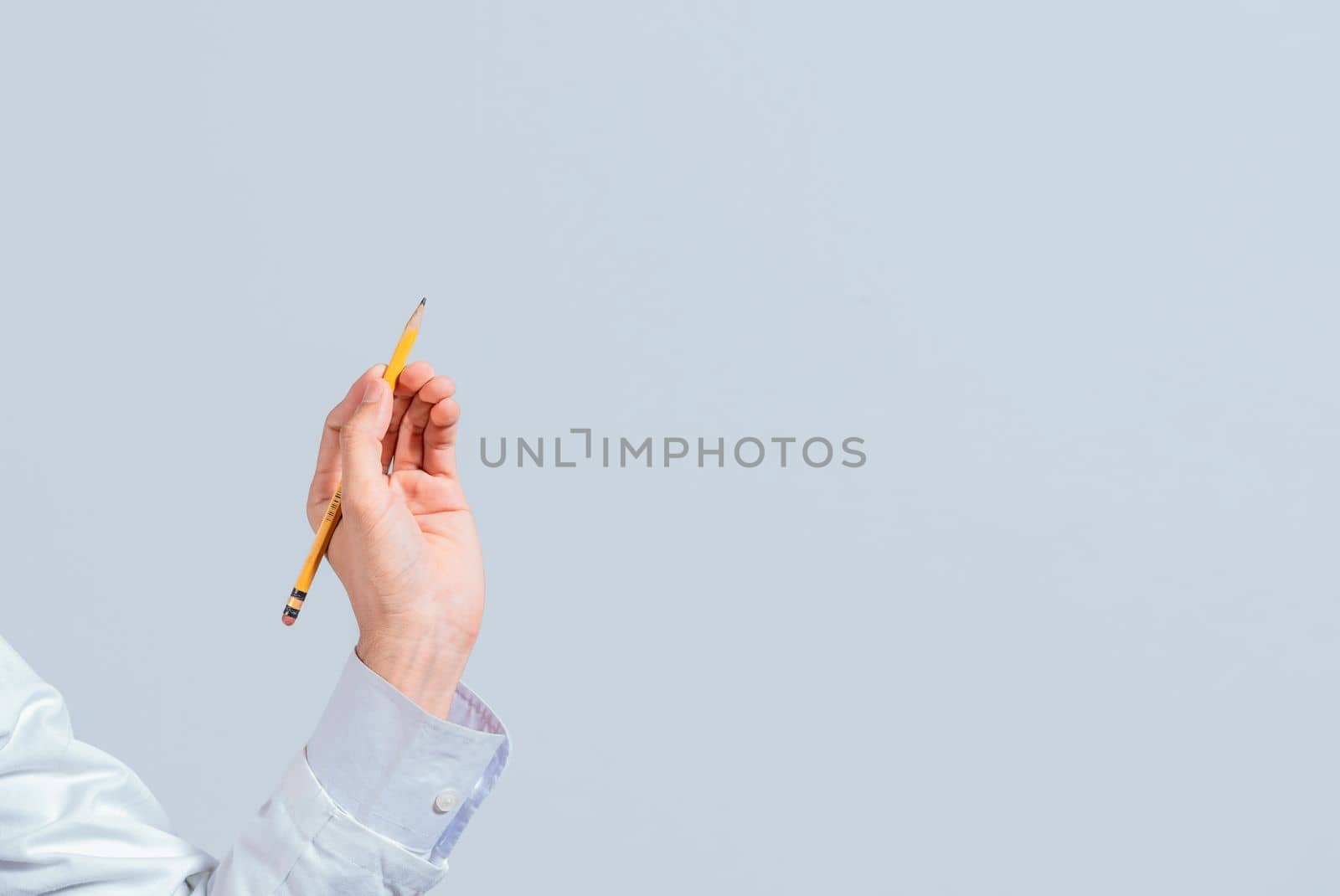 Hand with a pencil pointing at a blank space. Male hand holding a pencil on a blank. Man fingers holding a pencil with blank space. Person's hands holding a pencil on a space for text by isaiphoto