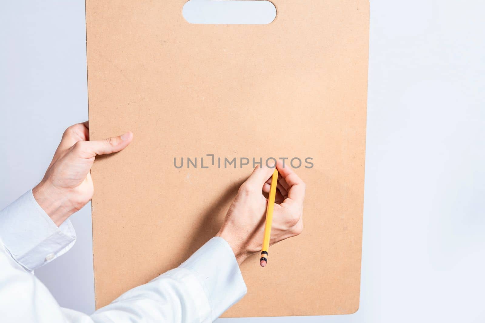 Close up of doctor hands with pencil over clipboard with copy space. Doctor hands writing on blank wooden clipboard isolated. Concept of hands writing on blank wooden clipboard
