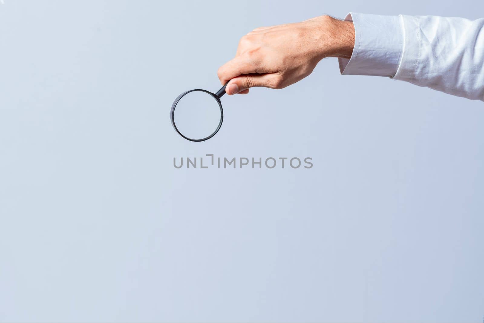 Hand holding magnifying glass on isolated background. Man's hand holding magnifying glass on white background. Hand holding magnifying glass looking for something with space for text