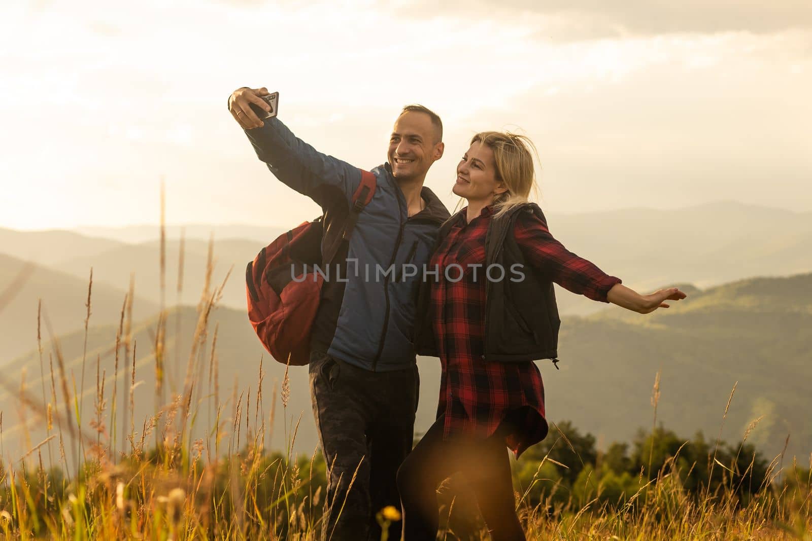 Man and woman standing and hugging on the top of the mountain, autumn hike with backpacks by Andelov13