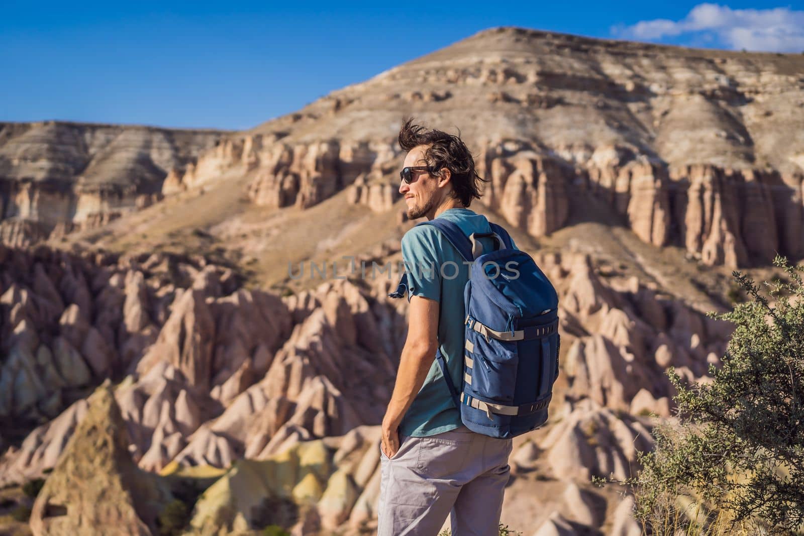 Young man exploring valley with rock formations and fairy caves near Goreme in Cappadocia Turkey.