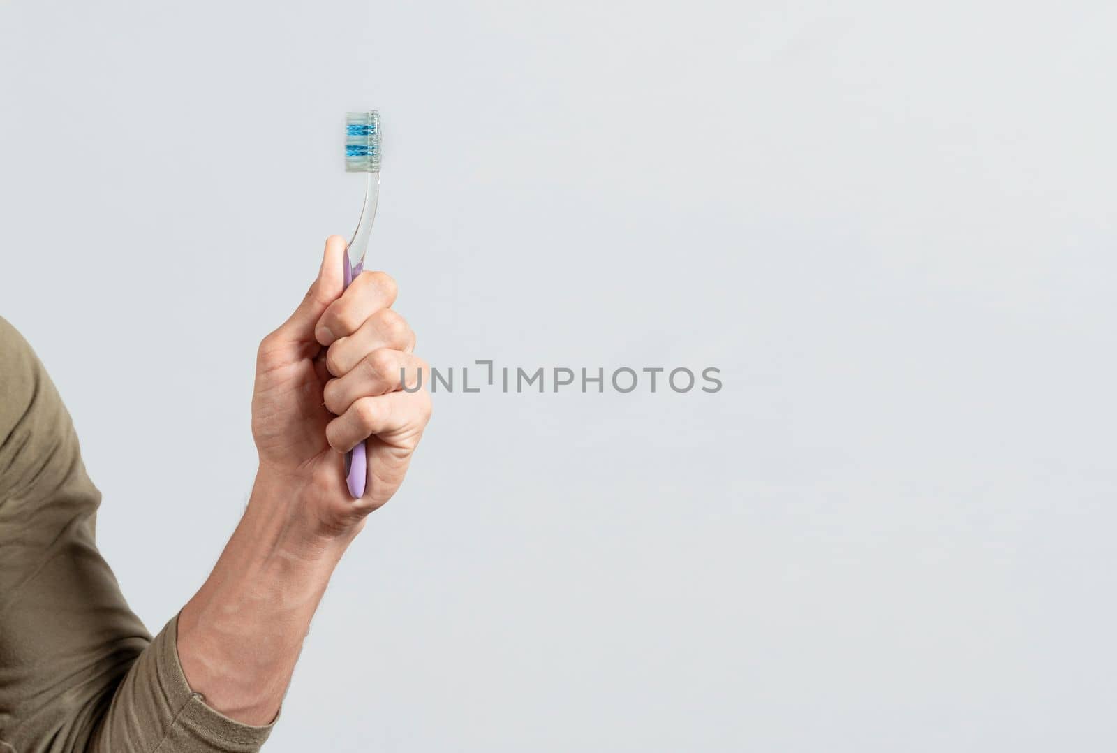 Hand holding toothbrush isolated on white. Male hand showing a toothbrush isolated. Toothbrush concept. by isaiphoto