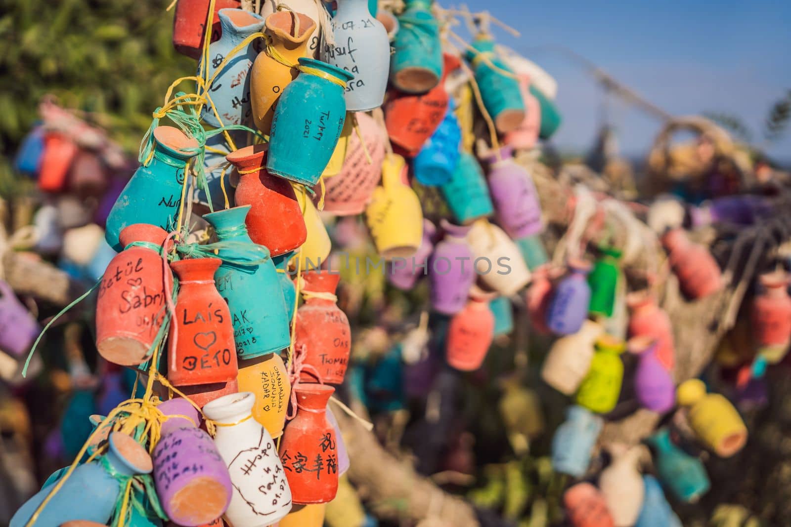 Wish tree. Small multi-colored jugs with inscriptions, wishes hanging on the branches of a tree., against the backdrop of sand ruins and blue sky.