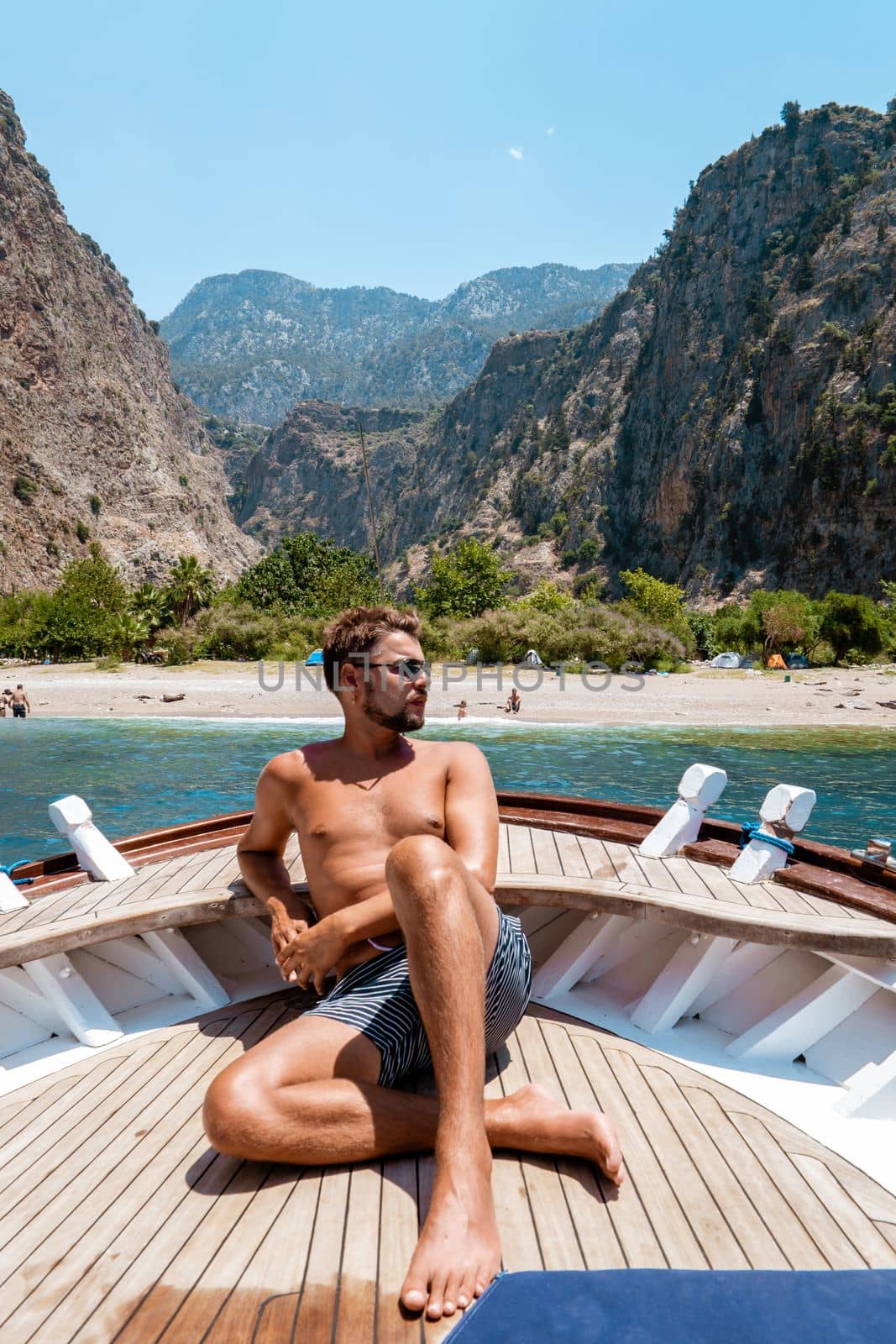 young man relaxing on a wooden boat during a boat trip to Butterfly beach at Fethiye Turkey by fokkebok