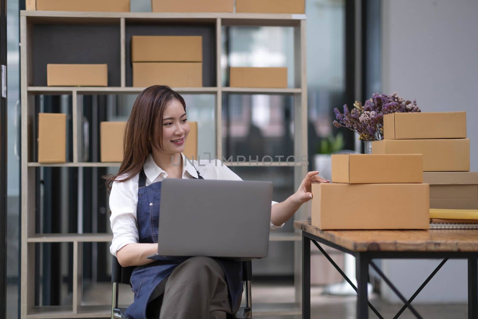 A portrait of a small startup, an SME owner, an Asian female entrepreneur checking orders to arrange the produce before packing the products in the inner boxes with the customers. Freelance concepts..