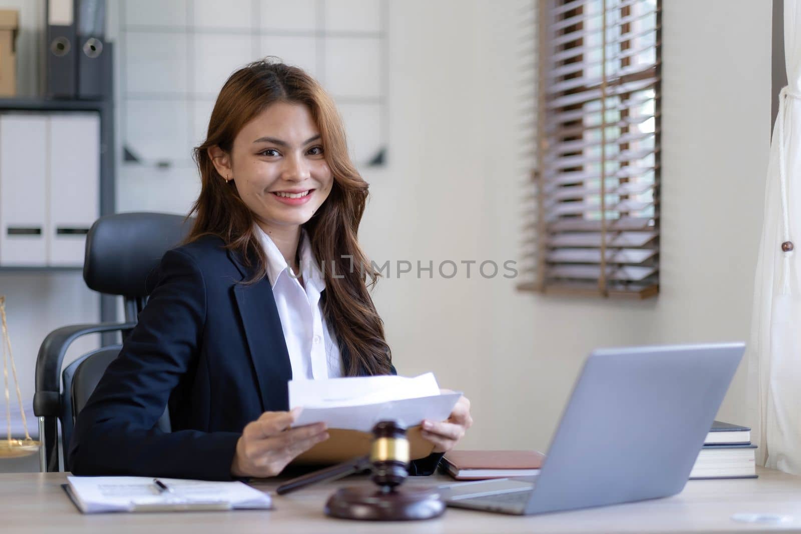 Attractive young lawyer in office Business woman and lawyers discussing contract papers with brass scale on wooden desk in office. Law, legal services, advice, Justice and real estate concept...