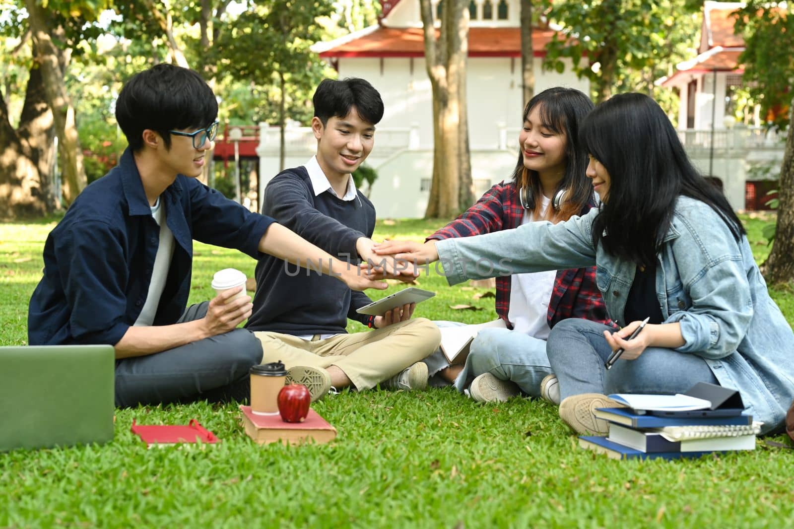 Happy university students stacking hands, celebrating together. University, youth lifestyle and friendship concept.