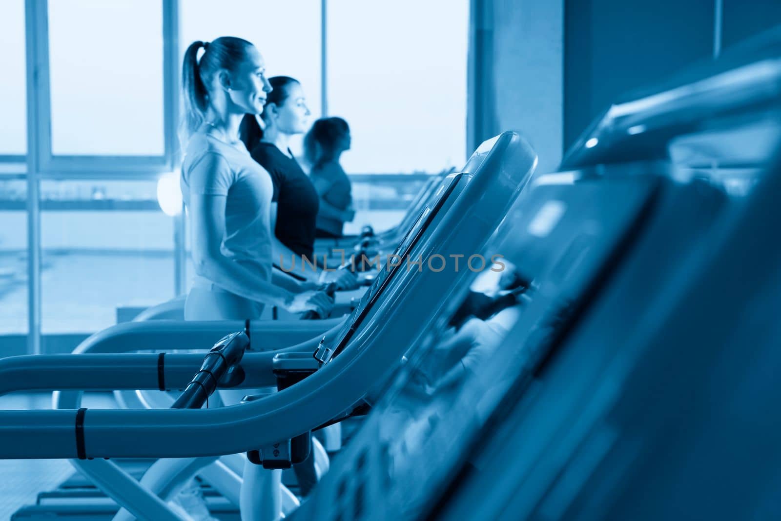 Young woman running on treadmill by Mariakray