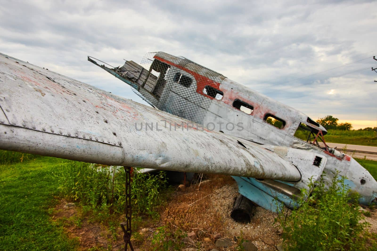 Cloudy day looking at destroyed airplane in field with focus on wing by njproductions