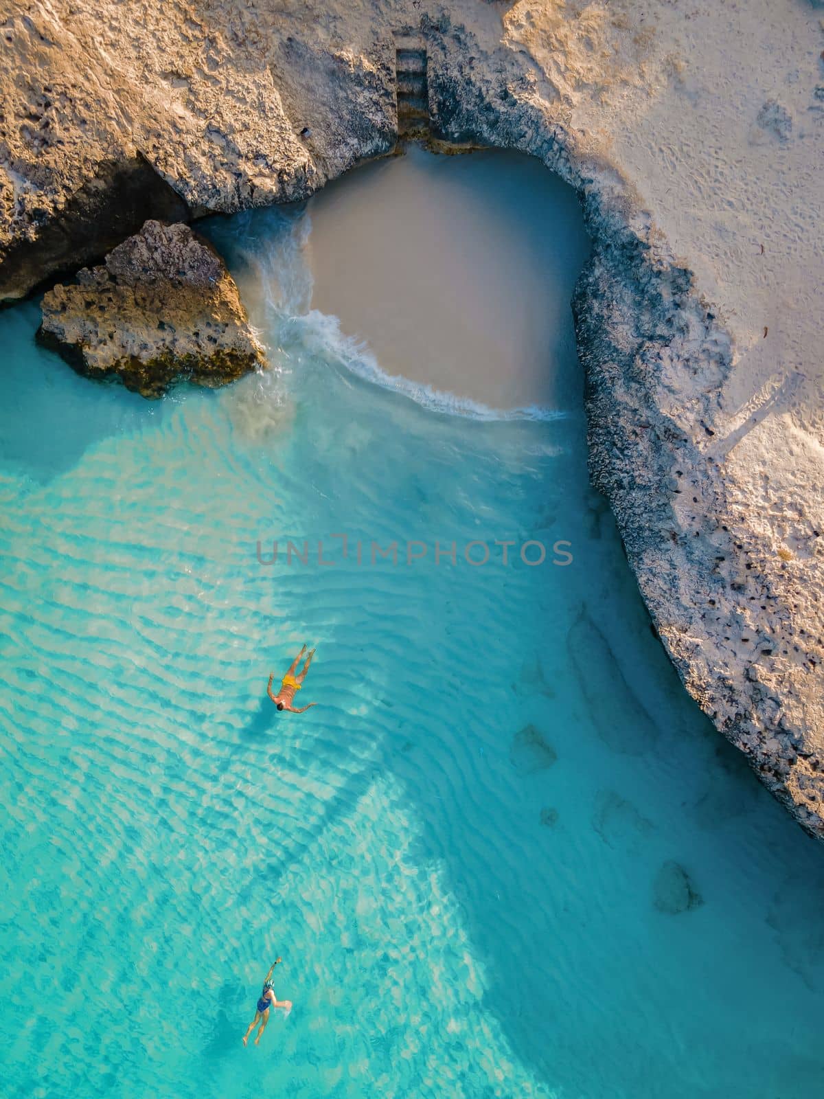 Tres Trapi Steps Triple Steps Beach, Aruba completely empty, Popular beach among locals and tourists, and crystal clear ocean Aruba. Caribbean, men swimming in blue ocean